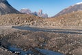 Wild river winds through remote, stony arctic landscape. A big moraine and iconic mountains on the horizon. Mt. Asgard