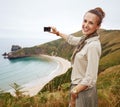 Woman hiker taking photo in front of ocean view landscape Royalty Free Stock Photo