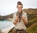 Woman hiker viewing photos in front of ocean view landscape