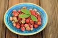 Wild strawberries Fragaria viridis in blue plate with green strawberry leaf selective focus Royalty Free Stock Photo