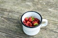 Wild strawberry in metal cup on wooden background