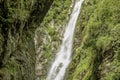 A wild waterfall in the rocks with grass