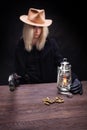 Wild west blonde girl shooting from gun at the table with ammunition and silver coins Royalty Free Stock Photo