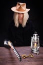 Wild west blonde girl shooting from gun at the table with ammunition and silver coins Royalty Free Stock Photo