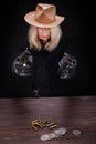 Wild west blonde girl shooting from revolver gun at the table with ammunition and silver coins Royalty Free Stock Photo