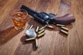 Wild west revolver and ammunitions with glass of whisky and ice with old silver dollar on wooden table