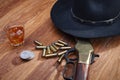 Wild west rifle and ammunitions with glass of whisky and ice with old silver dollar on wooden table