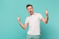 Wild young man in casual clothes screaming, showing horns up gesture, heavy metal rock sign isolated on blue turquoise Royalty Free Stock Photo