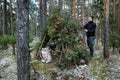 Wilderness survival camp - man building tree branch hut in forest in winter Royalty Free Stock Photo