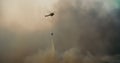 Wildfire on forest firefight helicopter fly over smoke and drop water to fire