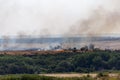 Wildfire or natural fire in fields with trees ands grass, dark smoke