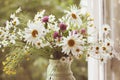 Wildflowers along with daisies in ceramic vase in vintage styl.
