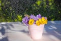 Wildflowers in white decorative bucket on wooden surface against background of greenery. Royalty Free Stock Photo