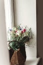 wildflowers in wicker bag on rustic white window. colorful flowers in brown basket in sunlight, space for text. rural atmospheric Royalty Free Stock Photo