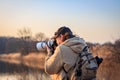 Wildlife photographer with camera photographing bird on lake at sunset Royalty Free Stock Photo