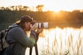 Wildlife photographer with camera photographing nature on lake at sunset Royalty Free Stock Photo
