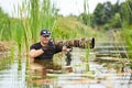 Wildlife photographer outdoor, standing in the water. Wildlife photographer in summer time working in the wild. Wildlife Royalty Free Stock Photo