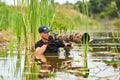 Wildlife photographer outdoor, standing in the water. Wildlife photographer in summer time working in the wild. Wildlife