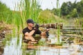 Wildlife photographer outdoor, standing in the water. Wildlife photographer in summer time working in the wild. Wildlife