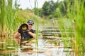 Wildlife photographer outdoor, standing in the water. Wildlife photographer in summer time working in the wild. Wildlife Royalty Free Stock Photo