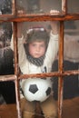 Will it ever stop raining. a sad little boy holding a soccer ball while watching the rain through a window. Royalty Free Stock Photo