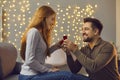 Happy young man proposing to his beloved woman and giving her gold engagement ring Royalty Free Stock Photo