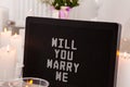 Will you marry me. The inscription on the card to a friend. Greeting for a wedding proposal with candles background Royalty Free Stock Photo