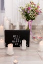 Will you marry me. The inscription on the card to a friend. Greeting for a wedding proposal with candles background Royalty Free Stock Photo