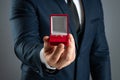 Will you marry me, A man in a business suit holds out in his hand a red box with a wedding ring. Concept of marriage proposal, Royalty Free Stock Photo