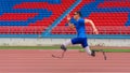 Willful Asian athlete speeds up on stadium track, aiming to break his record with prosthetic blades Royalty Free Stock Photo