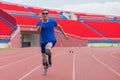 Willful Asian male athlete with prosthetics takes off speedily to surpass his running record on stadium track, motion blur depicts