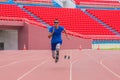 Willful Asian male athlete with prosthetics takes off speedily to surpass his running record on stadium track, motion blur depicts