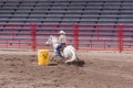 Woman on white horse cutting around barrel at barrel race