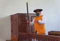 A man in colonial costume inside a Court House assisting visitors during a tour