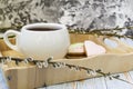 A willow twig with buds and a white cup of tea stands on a wooden tray. The concept of morning, breakfast Royalty Free Stock Photo