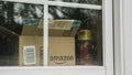 Wilson, NY, USA, July 2019: An open box from the parcel with the Amazon logo is visible outside the window. Royalty Free Stock Photo