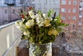 A wilted frozen bouquet of white roses and chrysanthemums, greenery in a crystal vase on open window under the sunlight against Royalty Free Stock Photo