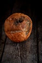 Wilted rotten apple with fungus on a wooden brown surface background