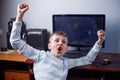 Win the game. Happy jubilant boy playing computer game in his ro