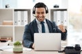 A win for one is a win for all. a young male call center agent cheering while using a laptop in an office at work. Royalty Free Stock Photo