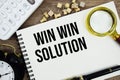 Win Win Solution text written on notepad with pen, alarm clock, magnifying glass and calculator on wooden background Royalty Free Stock Photo