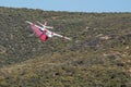 Winchester, CA USA - June 14, 2020: Cal Fire aircraft drops fire retardant on a dry hilltop wildfire near Winchester, California