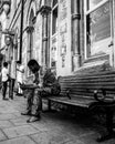 03/08/2020 Winchester, Hampshire, UK a black man wearing traditional african dress sitting on a bench looking at his mobile phone