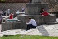 A man in business clothing sitting on the steps of a war memorial using his mobile phone all