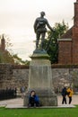 11/06/2019 Winchester, Hampshire, UK a young woman sitting against a statue of a soldier whilst using her mobile phone or cell