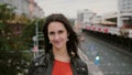 Wind blows long hair beautiful young women. happy, smiling girl standing on the bridge and looks at the camera 4K Royalty Free Stock Photo