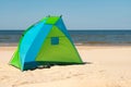 Wind breaker tent on a sandy beach by the sea. Nobody. Colorful tent protection from wind and sunburn