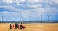 Wind farm off the coast of Yarmouth with family walking dogs on beach in Great Yarmouth, Norfolk, UK Royalty Free Stock Photo
