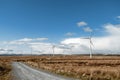 Wind farm in an open field. Green electric energy generation. Warm sunny day. Power supply industry