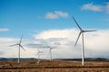 Wind farm in an open field. Green electric energy generation. Warm sunny day. Power supply industry